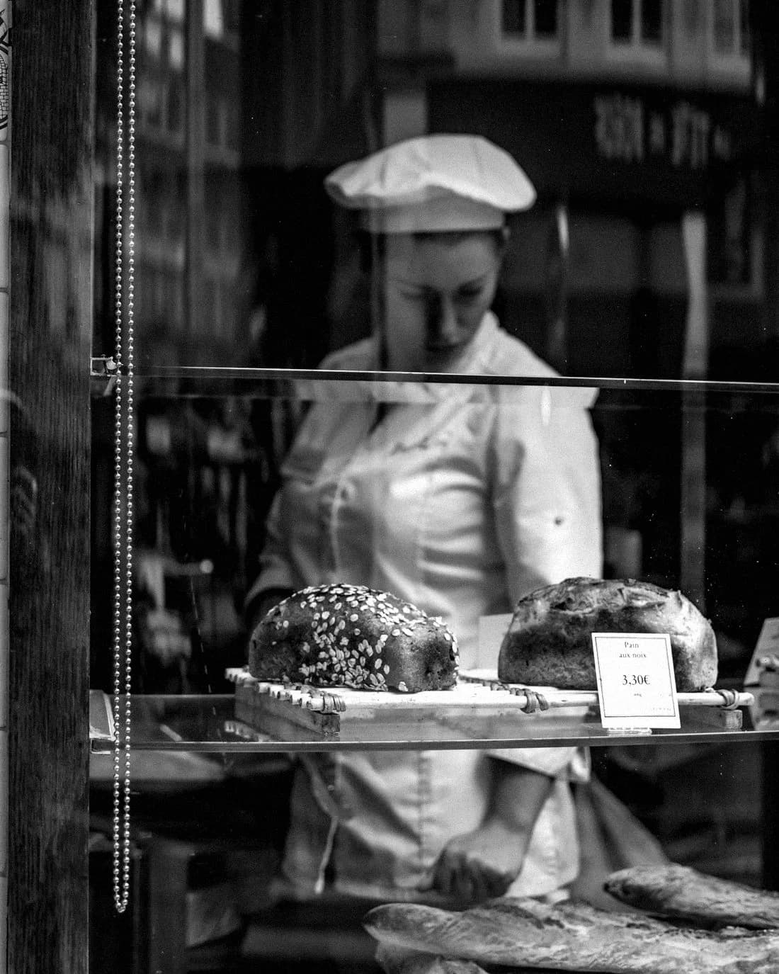 Panadera colocando pan en el escaparate de su tienda